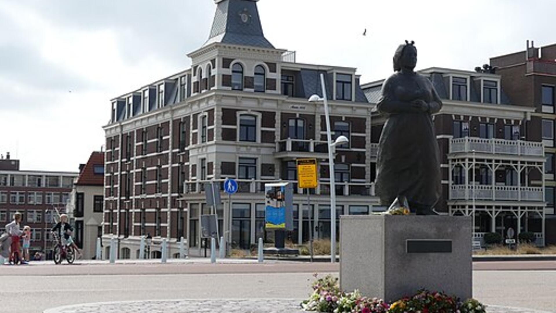 Vissersvrouw van Scheveningen met op de achtergrond bebouwing 
